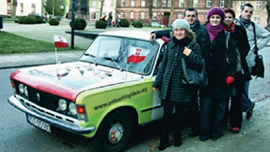 Familie mit Migrationshintergrund vor grün-rotem Wagen